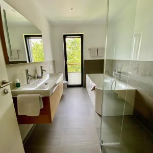 baño con 2 lavabos y ducha de cristal en FeWo Bodenseewest, en Salenstein