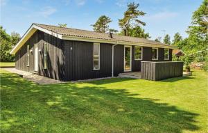 uma casa preta com um relvado verde em frente em Amazing Home In Ebeltoft With Kitchen em Ebeltoft