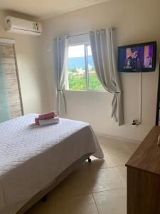 a bedroom with a bed and a window with a tv at Pousada Guesthouse in Timbó