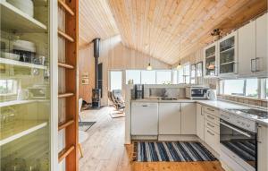 エーベルトフトにあるGorgeous Home In Ebeltoft With Kitchenの白いキャビネットと木製の天井が備わるキッチン
