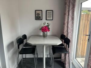 una mesa de comedor con un jarrón de flores. en Salford Townhouse 3 BR Home, en Mánchester
