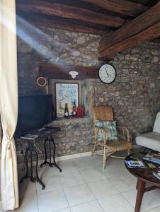 a living room with a clock on a stone wall at Domaine viticole Philippe Deschamps in Beaujeu