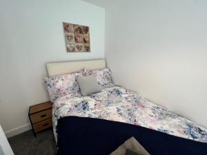 1 dormitorio con 1 cama con colcha de flores en Salford Townhouse 3 BR Home, en Mánchester