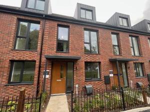 um edifício de tijolos vermelhos com uma porta castanha em Salford Townhouse 3 BR Home em Manchester