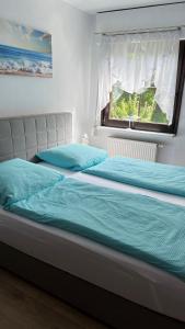 a bedroom with two beds with blue sheets and a window at Ferienwohnung Stockrose in Lohme