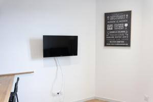 een flatscreen-tv aan een witte muur bij LE BISTROT 203 - Tout équipé - WIFI & TV in Saint-Chamond