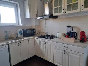 a kitchen with white cabinets and a stove top oven at Magic Garden - Pool, Events, Free Parking in Tărtăşeşti