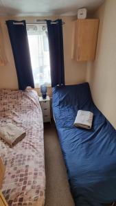 1 dormitorio con 2 camas con sábanas azules y ventana en Loch Earn Holiday Home, en St Fillans