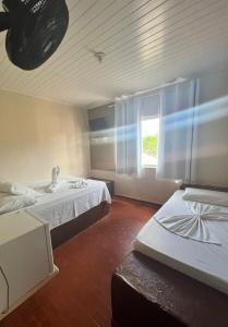 a hotel room with two beds and a window at Hotel Gruta da Serra in Guaramiranga