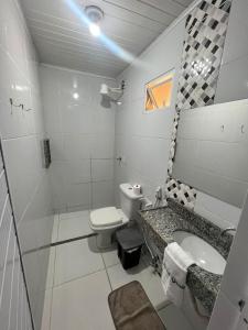 a white bathroom with a toilet and a sink at Hotel Gruta da Serra in Guaramiranga