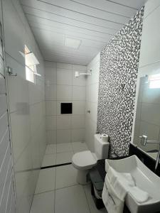 Baño blanco con aseo y lavamanos en Hotel Gruta da Serra en Guaramiranga