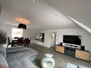 a living room with a couch and a tv and a table at Ferienwohnung, schön & modern, Strand/ -Grimmershörnbucht in Cuxhaven