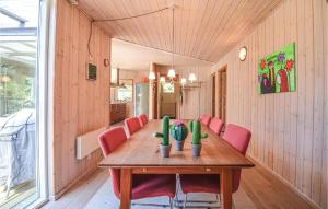 Nice Home In Ebeltoft With Kitchen في Øksenmølle: غرفة طعام مع طاولة خشبية وكراسي حمراء