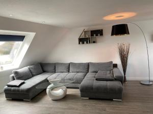 ein Wohnzimmer mit einem grauen Sofa und einem Tisch in der Unterkunft Ferienwohnung, schön & modern, Strand/ -Grimmershörnbucht in Cuxhaven