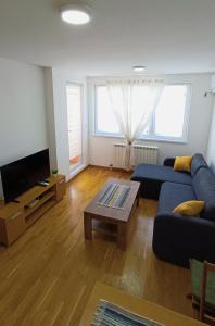 un salon avec un canapé bleu et une télévision dans l'établissement Felix Apartment Istocno Sarajevo, à Vranješ