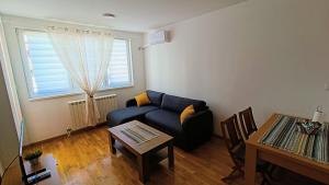 - un salon avec un canapé bleu et une table dans l'établissement Felix Apartment Istocno Sarajevo, à Vranješ