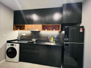 a black kitchen with a sink and a refrigerator at The Axon Suites Bukit Bintang By Cozy Stay in Kuala Lumpur