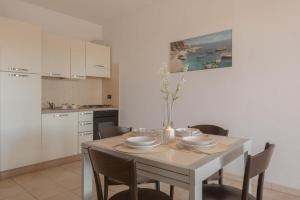 a kitchen with a table with chairs and a dining room at Stylish Residence Le Fontane no2503 in Villasimius