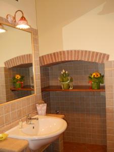 Un baño con lavabo, espejo y flores. en Agriturismo Valiana, en Montegabbione