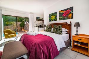 um quarto com uma cama, uma cadeira e uma janela em 5 Rembrandt Guesthouse em Somerset West