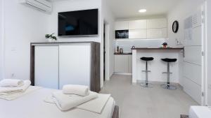 een witte kamer met een tv en een keuken bij Apartmani Vegas in Novalja