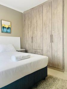 ハボローネにあるCandlewood Apartment 8の白いベッドと木製キャビネット付きのベッドルーム1室