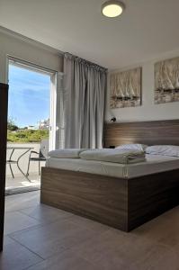 een slaapkamer met een groot bed en een groot raam bij Apartmani Vegas in Novalja