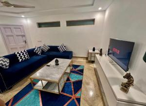 a living room with a blue couch and a tv at Homtel Signature Suites in Islamabad