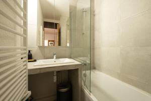 a bathroom with a sink and a tub and a mirror at L'Arc-en-Ciel - Appartement sur les hauteurs du Mottaret avec accès aux pistes in Les Allues