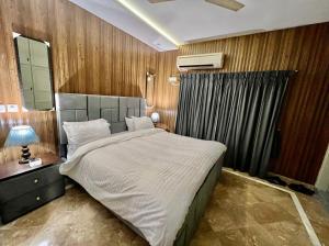 1 dormitorio con 1 cama grande y espejo en Homtel Signature Suites, en Islamabad