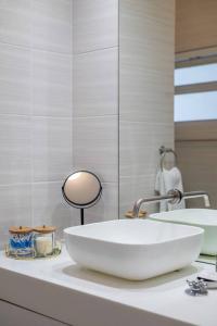 een witte badkamer met een wastafel en een spiegel bij Seaside Studio in Mouille Point in Kaapstad