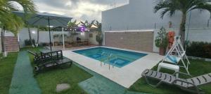 una piscina con sillas y sombrilla en Cabaña villa kary en Barranquilla