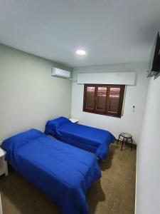 três camas num quarto com lençóis azuis em Hotel FG em Termas de Rio Hondo