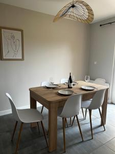 comedor con mesa de madera y sillas blancas en Appartement Deluxe - Spa & Sauna en Trégastel