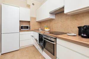 Una cocina con gabinetes blancos y una estufa. en Warm & Bright City Vibe Apartment with 1 Bedroom in Gdańsk-Wrzeszcz by Noclegi Renters, en Gdansk