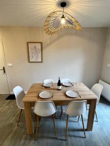 mesa de comedor con sillas blancas y lámpara en Appartement Deluxe - Spa & Sauna en Trégastel