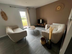 Una sala de estar con dos sillas blancas y un televisor. en Scorfel Lodge, Iconic, Spa, sauna & terrasse, en Trégastel
