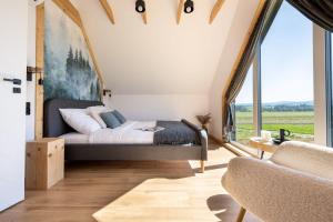 1 dormitorio con cama y ventana grande en Bliżej GÓR- nowoczesne domki w górach z balią, en Ostrowsko