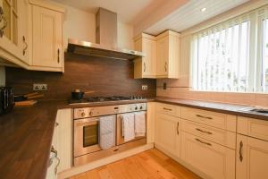 a kitchen with white cabinets and a stove top oven at Luxurious & Tranquil Riverside Getaway in Great Harwood
