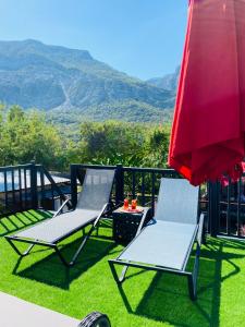 duas cadeiras e um guarda-sol vermelho numa varanda com montanhas em Garden Bungalow em Antalya