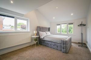 a bedroom with a large bed and two windows at Luxurious & Tranquil Riverside Getaway in Great Harwood
