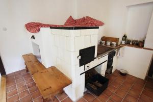 a kitchen with a fireplace with a table and a bench at Roubenka U Andělů, Šumava in Kašperské Hory