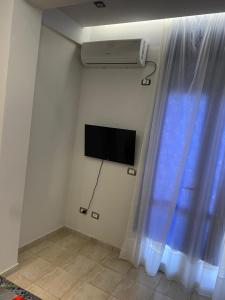 um quarto com uma televisão e uma janela com uma cortina em Floger world em Vlorë