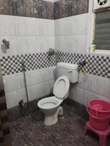a bathroom with a toilet and a red bucket at Asha vihara Phase-2 in Muzaffarpur