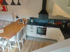 a kitchen with white cabinets and a wooden counter top at Tannerie 4 in Lanvallay