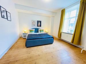 a bedroom with a blue bed and a wooden floor at aday - Sunshine apartment in the heart og Hjorring in Hjørring