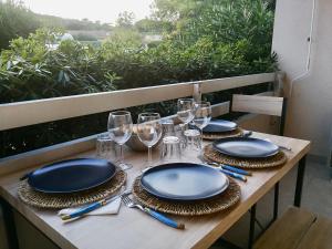 a table with plates and wine glasses on it at Grand studio Standing avec terrasse et parking in Sainte-Maxime