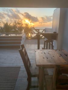 a wooden table and bench on a balcony with the sunset at Zi Loft Beach Cottage in Matemwe