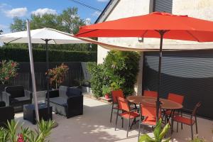 a patio with a table and chairs and an umbrella at Gîte Sweetloire in La Menitré