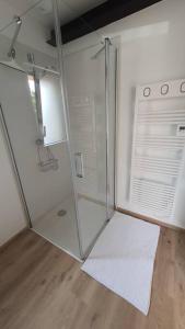 a glass shower in a room with a wooden floor at Gîte Sweetloire in La Menitré